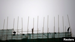 FILE - Laborers work at a construction site in Beijing.