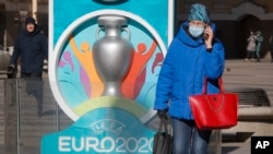 A woman wears a medical mask walks past a sign with Euro 2020 emblem in St.Petersburg where UEFA planned to host four UEFA EURO 2020 matches, including a quarter final, in Russia, March 17, 2020. 