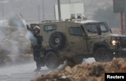 FILE - An Israeli border police officer fires tear a gas canister during clashes with Palestinian protesters near the Jewish settlement of Bet El, near the West Bank city of Ramallah, Nov. 5, 2015.
