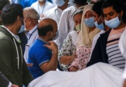 Saira Banu, wife of Indian actor Dilip Kumar, wearing blue mask, center, mourns near his body at a hospital in Mumbai, India, July 7, 2021.