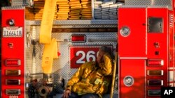 A firefighter leans against his fire truck while resting from working on a wildfire in Los Angeles, Monday, Oct. 28, 2019.