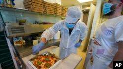 Olive oil is put on a pizza ready to be home delivered, at the Caputo pizzeria in Naples, Italy, April 27, 2020, as region Campania allowed cafes and pizzerias to reopen for delivery after a long precautionary closure due to the coronavirus outbreak.