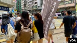 香港言语治疗师总工会主席黎雯龄（手持旗帜者）与两名成员，今年7-1在港岛铜锣湾及湾仔一带做”流动街站”，呼吁市民继续发声，争取民主 (美国之音/汤惠芸)