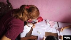 Beatriz Arráiz, docente venezolana con 12 años de experiencia, conversa con una alumna desde la sala de su casa, convertida hoy en un aula escolar, en Caracas. [Foto: VOA/Adriana Núñez Rabascall].