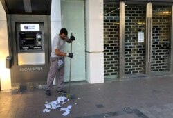 A worker cleans receipts from an ATM machine outside a closed Blom Bank branch in the southern city of Sidon, Lebanon, Nov. 12, 2019.