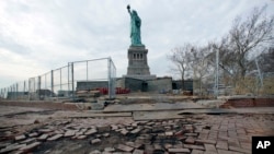 FILE - The Statue of Liberty stands beyond parts of a brick walkway damaged in Superstorm Sandy on Liberty Island in New York, Nov. 30, 2012. With scientists forecasting sea levels to rise by anywhere from several inches to several feet by 2100, historic structures and coastal heritage sites around the world are under threat. 