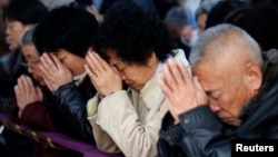 FILE - Believers take part in a weekend mass at an underground Catholic church in Tianjin.