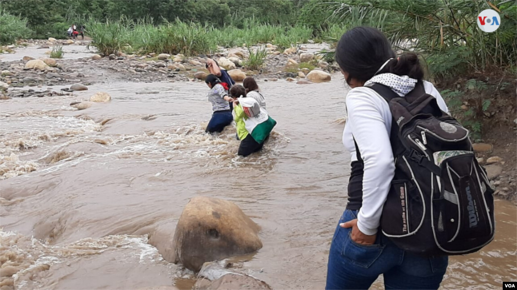 Las lluvias recientes subieron el nivel de las aguas del río, pero, con esfuerzo, este grupo de personas cruzó hacia Venezuela. (Foto: Hugo Echeverry)