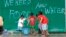 Children help to carry pails of drinking water as they walk past graffiti calling for help after Typhoon Haiyan devastated Tacloban city, central Philippines, Nov. 12, 2013.