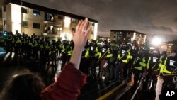 A demonstrator raises their hand while facing off against a perimeter of police as they defy an order to disperse during a protest against the police shooting of Daunte Wright, April 12, 2021, in Brooklyn Center, Minn.