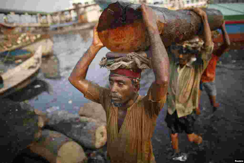 Workers carry a log at a timber factory by the river Buriganga in Dhaka, Bangladesh.