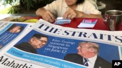 A news vendor counts her money near a stack of newspapers with a photo of U.S. President Donald Trump, right, and North Korea's leader Kim Jong Un on its front page on May 11, 2018, in Singapore. 