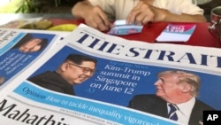 A news vendor counts her money near a stack of newspapers with a photo of U.S. President Donald Trump, right, and North Korea's leader Kim Jong Un on its front page on Friday, May 11, 2018, in Singapore. U.S. President Donald Trump will meet with North Korea's leader Kim Jong Un in Singapore on upcoming June 12, Trump announced in a Tweet Thursday. Singapore's diplomatic ties with North Korea and its relative proximity made the small Southeast Asian nation a natural choice for the historic summit between President Donald Trump and North Korean leader Kim Jong Un, analysts say. (AP Photo/Wong Maye-E) 