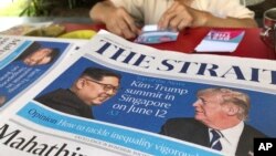 A news vendor counts her money near a stack of newspapers with a photo of U.S. President Donald Trump, right, and North Korea's leader Kim Jong Un on its front page on Friday, May 11, 2018, in Singapore. U.S. President Donald Trump will meet with North Korea's leader Kim Jong Un in Singapore on upcoming June 12, Trump announced in a Tweet Thursday. Singapore's diplomatic ties with North Korea and its relative proximity made the small Southeast Asian nation a natural choice for the historic summit between President Donald Trump and North Korean leader Kim Jong Un, analysts say. (AP Photo/Wong Maye-E) 