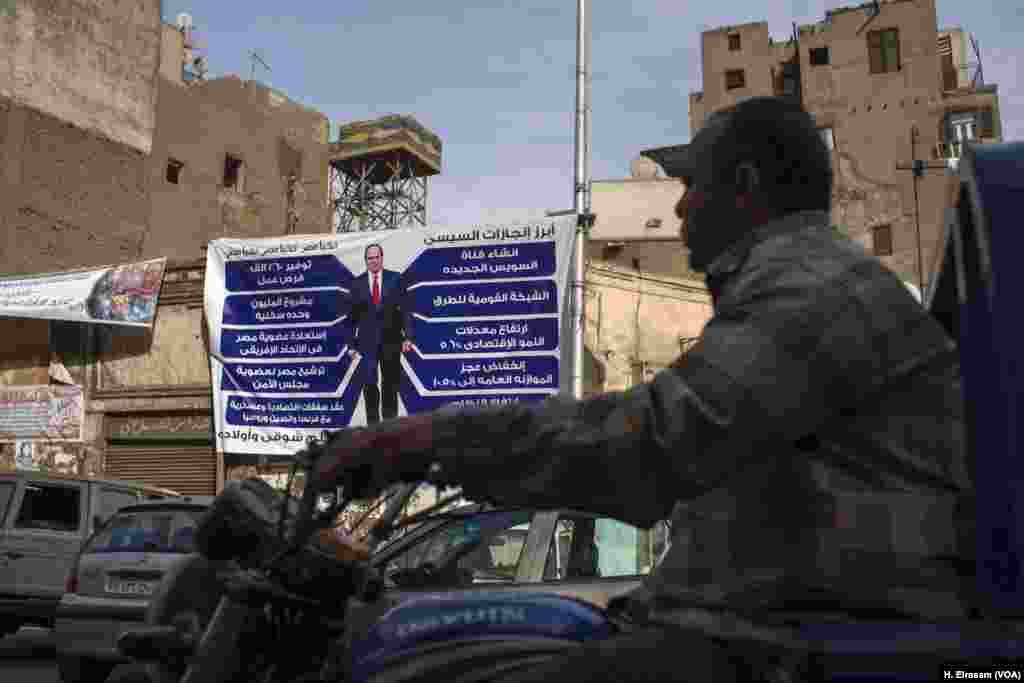 A man riding a motorbike in central Cairo passes by a campaign banner touting incumbent President Abdel Fattah el-Sissi's major achievements during his first term, March 9, 2018.