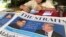 A news vendor counts her money near a stack of newspapers with a photo of U.S. President Donald Trump, right, and North Korea's leader Kim Jong Un on its front page on May 11, 2018, in Singapore. 