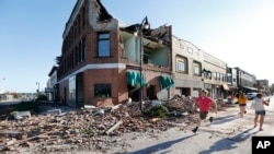 A local resident runs past a tornado-damaged building on Main Street, July 19, 2018, in Marshalltown, Iowa. 