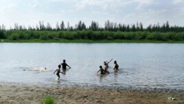 In this handout photo taken Sunday, June 21, 2020 and provided by Olga Burtseva, children play in the Krugloe lake outside Verkhoyansk, the Sakha Republic, about 4660 kilometers northeast of Moscow, Russia. (Olga Burtseva via AP)