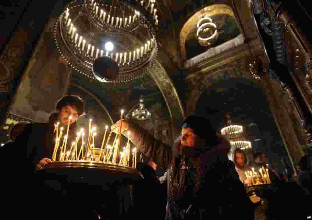 Masyarakat menyalakan lilin di sebuah gereja &nbsp;menandai perayaan Hari Natal bagi kaum Orthodox di Katedral Santo Volodymyr di Kyiv, Ukraine.