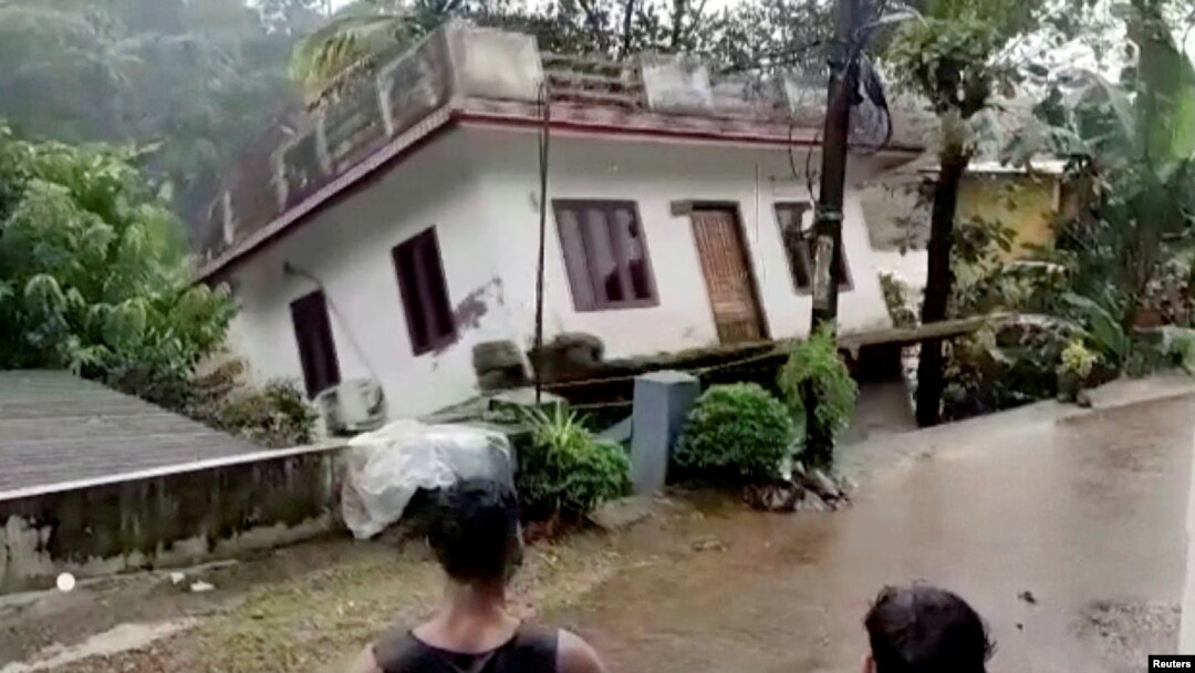 Orang-orang menyaksikan sebuah rumah yang hanyut terbawa arus sungai setelah hujan lebat melanda wilayah Kottayam, Kerala, India, pada 17 Oktober 2021. (Foto: Reuters TV/ANI/Kerala Government Public Relations Office/Handout via Reuters)