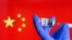 中国国旗前贴有新冠病毒疫苗标签的小瓶子