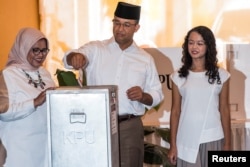 Anies Baswedan (C) is seen with his wife Fery Farhati Ganis (L) and his daughter Mutiara Annisa Baswedan as he casts his ballot during an election for Jakarta's governor in Jakarta, February 15, 2017 in this photo taken by Antara Foto.