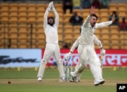 Afghanistan's Rashid Khan, right appeals unsuccessfully for the wicket of India's Dinesh Karthik, center partly seen, during their one-off cricket test match in Bangalore, India, June 14, 2018.