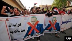 Iraqi demonstrators lift banners against Prime Minister Mustafa Al-Kadhimi during a protest rejecting last month's election result, near an entrance to the Green Zone in Baghdad, November 5, 2021.