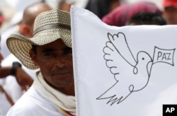 FILE - A rebel of the Revolutionary Armed Forces of Colombia, FARC, waves a white peace flag during an act to commemorate the completion of their disarmament process in Buenavista, Colombia, June 27, 2017.