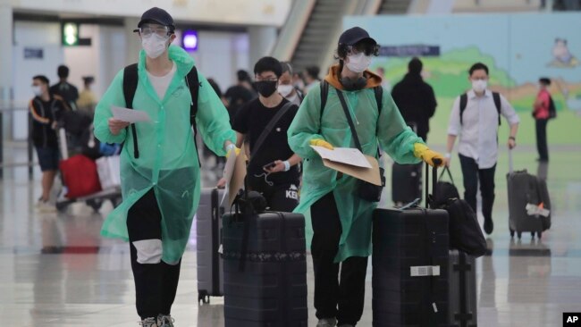 身穿防护服和戴口罩的旅客抵达香港国际机场。（2020年3月23日）
