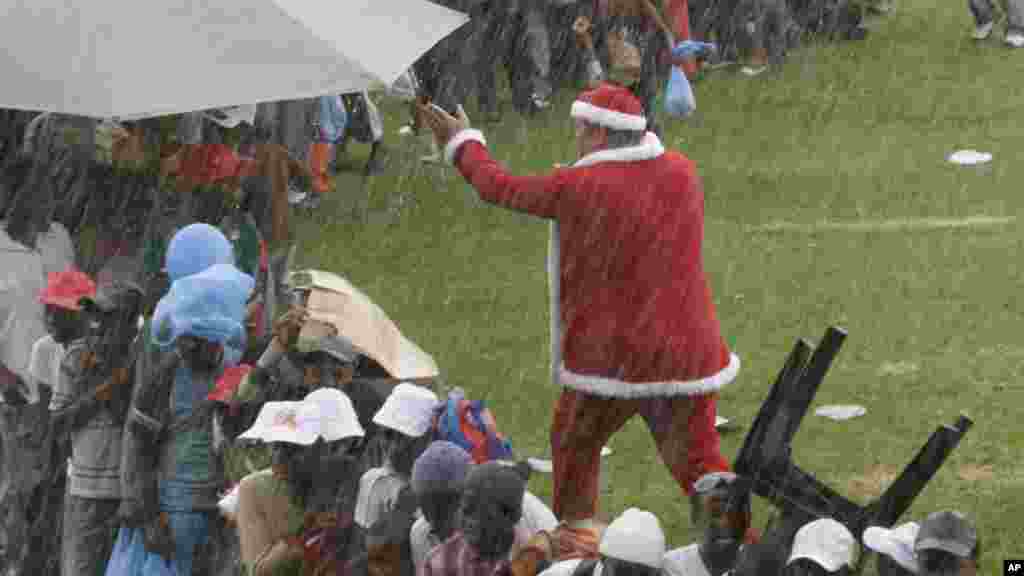 Un homme déguisé en Père est pris dans un orage au cours de la fête de Noël pour les enfants défavorisés dans Maraisburg, Afrique du Sud, 7 décembre 2008