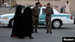 Des Saoudiennes passant à côté de policiers à Manfouha, dans le sud de Riyad, le 14 novembre 2013.