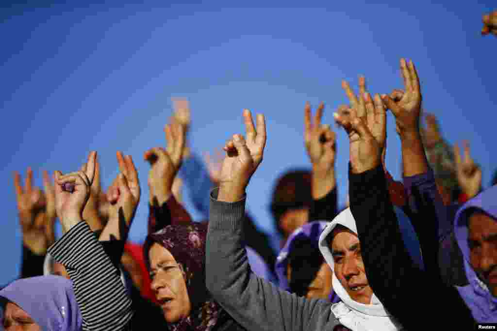 Perempuan-perempuan Kurdi dari Turki mengacungkan jari tanda kemenangan dalam pemakaman para pejuang Kurdi yang tewas dalam pertempuran dengan&nbsp;militan&nbsp;ISIS di Kobani, di TPU di Suruc, Turki (21/10).&nbsp;(Reuters/Kai Pfaffenbach) 