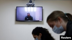 Russian opposition leader Alexei Navalny is seen on a screen via a video link during a hearing to consider his lawsuits against the penal colony over detention conditions there, at the Petushki district court in Petushki, Russia, May 26, 2021.