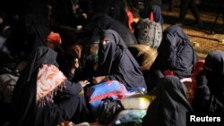 Women sit together with their belongings near the village of Baghouz, Deir Al Zor province, Syria, Feb. 25, 2019. 