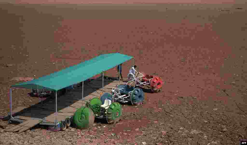 Pakistani residents inspect a three wheeler water bike standing over a dry portion of the Rawal dam in Islamabad.