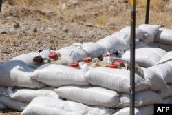 Explosive devices cleared by Iraqi mine clearers working for Halo Trust, a non-profit organization specialized in mine removal, are placed on sand bags in an agricultural and industrial field near the Iraqi town of Baiji, Aug. 25, 2019.