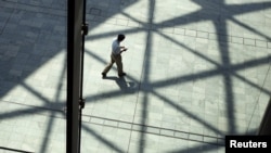 FILE - A man walks under the shadow of sunshade at a building in Tokyo. Would a man-made chemical sunshade — perhaps formed by clouds of reflective sulfur particles sprayed high in the Earth's atmosphere — be less risky than a harmful rise in global temperatures? It's a question scientists are trying to answer.