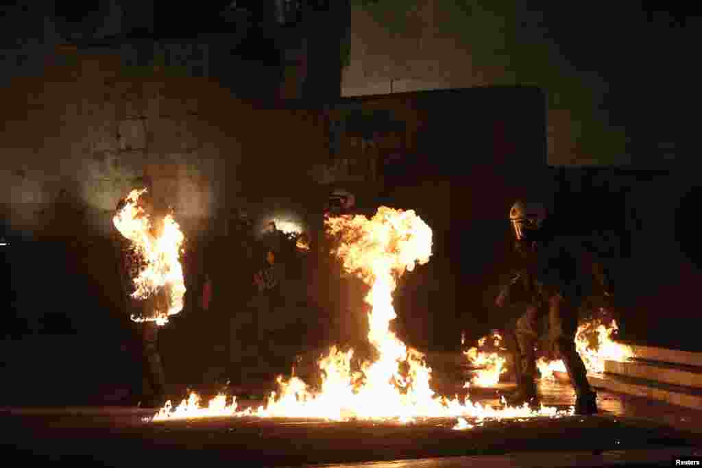 A masked demonstrator throws a petrol bomb aty riot police outside the parliament building as Greek lawmakers vote on the latest round of austerity, in Athens.