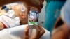 FILE - A doctor uses a smartphone to take a photo of a child with facial deformity before surgery at the Vietnam Cuba hospital in Hanoi, Vietnam.