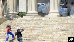 Students hurl stones on the University of the Witwatersrand campus in Johannesburg South Africa on Monday, Oct. 10, 2016. 