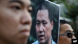 Demonstran anti-Beijing membawa foto pakar hukum hak asasi manusia, Pu Zhiqiang, protes di luar kantor liaison China menuntut pembmebasan Pu, di Hong Kong, Selasa, 15 Desember 2015.