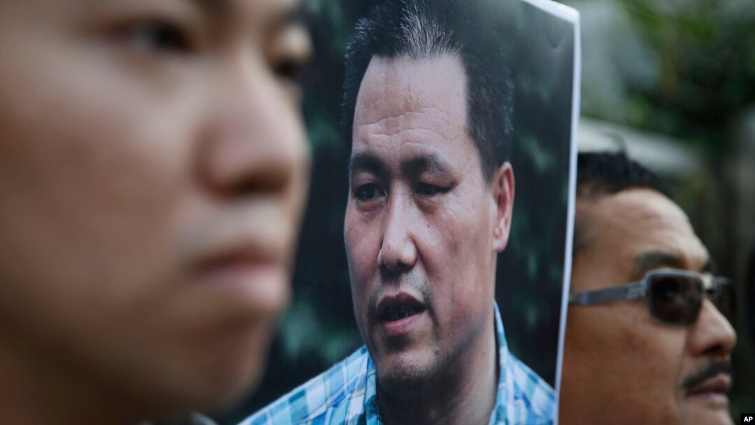 FILE - Anti-Beijing protesters, with a picture of human rights lawyer Pu Zhiqiang, protest outside the Chinese liaison office to demand Pu's release, in Hong Kong, Tuesday, Dec. 15, 2015.