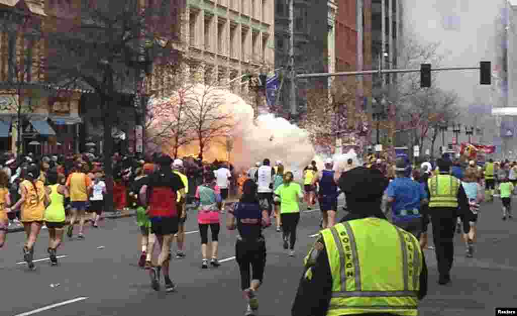 Para peserta terus berlari menuju garis akhir Marathon Boston saat ledakan muncul dekat garis finish, menewaskan tiga orang dan melukai lebih dari 250 lainnya (15/4). (Reuters/Dan Lampariello)