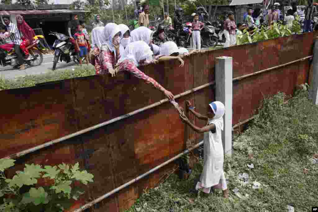 School children hand food to a young&nbsp;Rohingya girl at a temporary shelter in Bayeun, Aceh province, May 21, 2015.