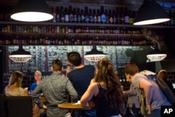 In this July 21, 2017 photo, people review the craft beer choices at the RULE Taproom pub.