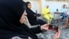 A displaced woman watches the speech of Hezbollah Vice Hezbollah Secretary General Naim Qassem on her phone inside a school transformed into a shelter for displaced families in Beirut on Oct. 8, 2024. 