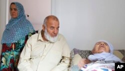 106-year-old Afghan refugee Bibihal Uzbeki rests in bed attended by her son Mohammadollah and daughter-in-law Ziba, in Hova, Sweden, Sept. 3, 2017.