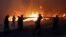 Firefighters, soldiers and local residents carry a hose as a wildfire burns in the town of Rafina, near Athens, Greece, July 23, 2018. 