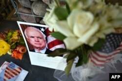 Foto, bunga, dan ucapan duka cita untuk menghormati Senator AS John McCain di depan kantornya di Phoenix, Arizona, 26 Agustus 2018.